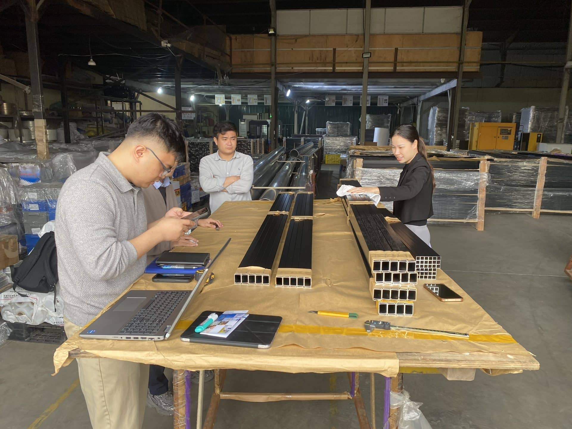 Team inspecting aluminium extrusion profiles on a factory workbench