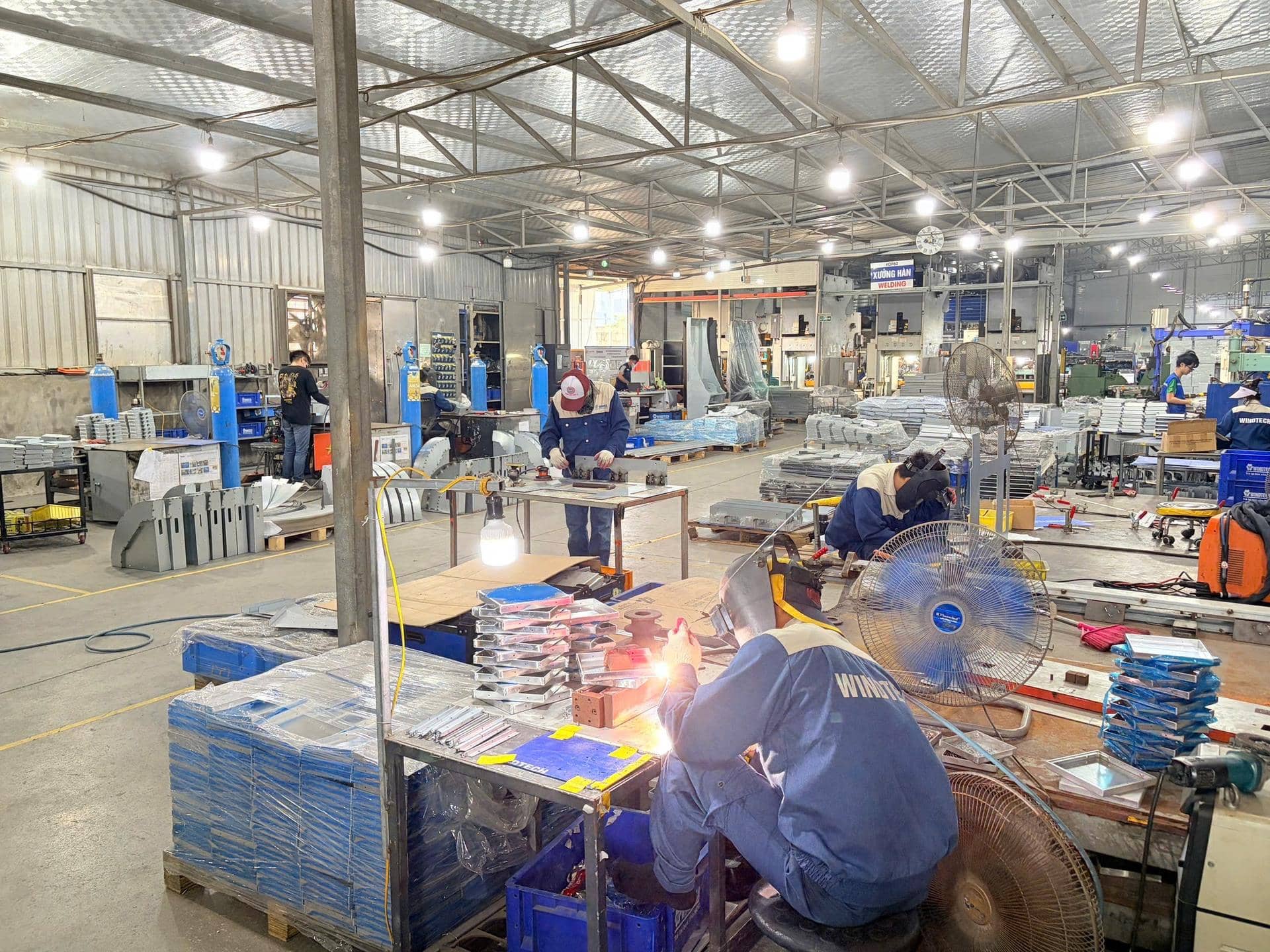 Welder working on sheet metal parts on a fabrication shop floor