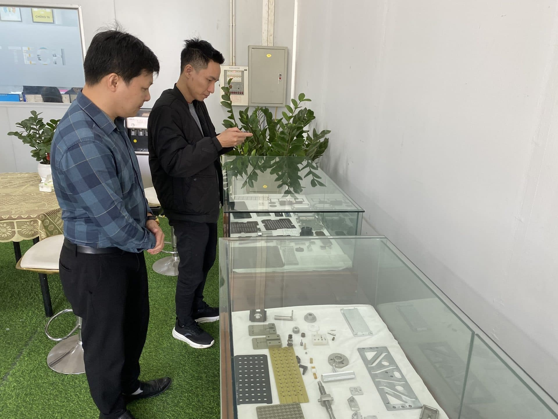 Buyers reviewing sample sheet metal and CNC parts in a factory showroom