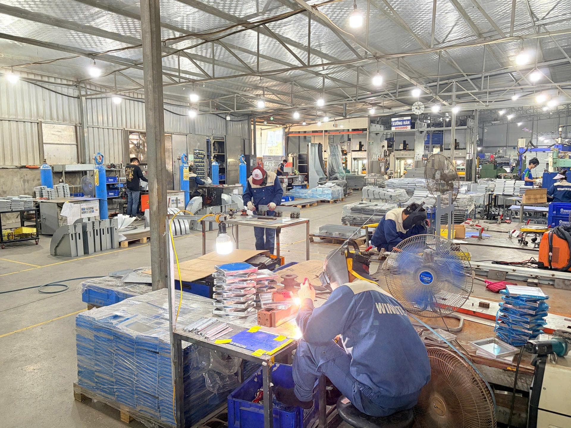 Welder working on sheet metal parts on a fabrication shop floor